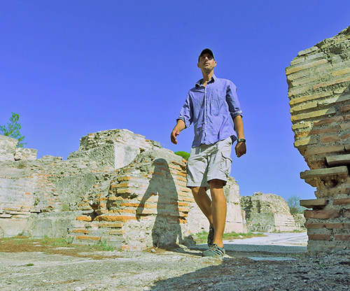 man in shorts and button down walking through rock ruins