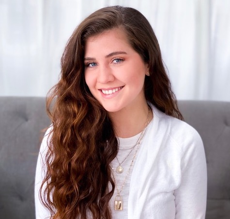 headshot of a girl with long brown hair wearing a white t-shirt