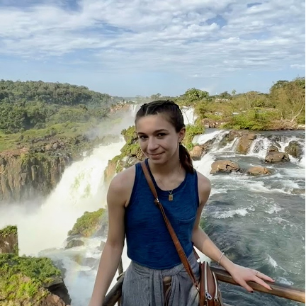A picture of a woman standing in front of a waterfall.