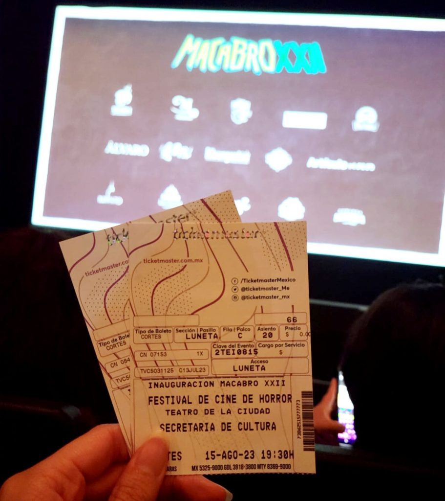 Photo of a two tickets that say "Festival De Cine De Horror" with a movie screen in the background that says "Macabro XXII."