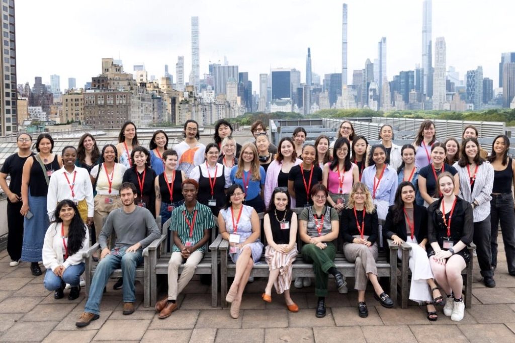 A group of 41 people smiling at the camera with the New York City skyline in the background.