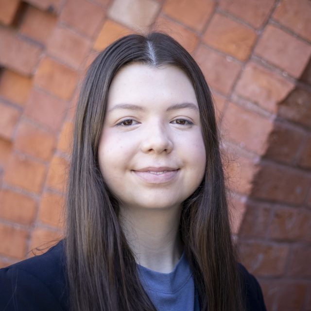 A picture of a woman with long black hair and a blue shirt.