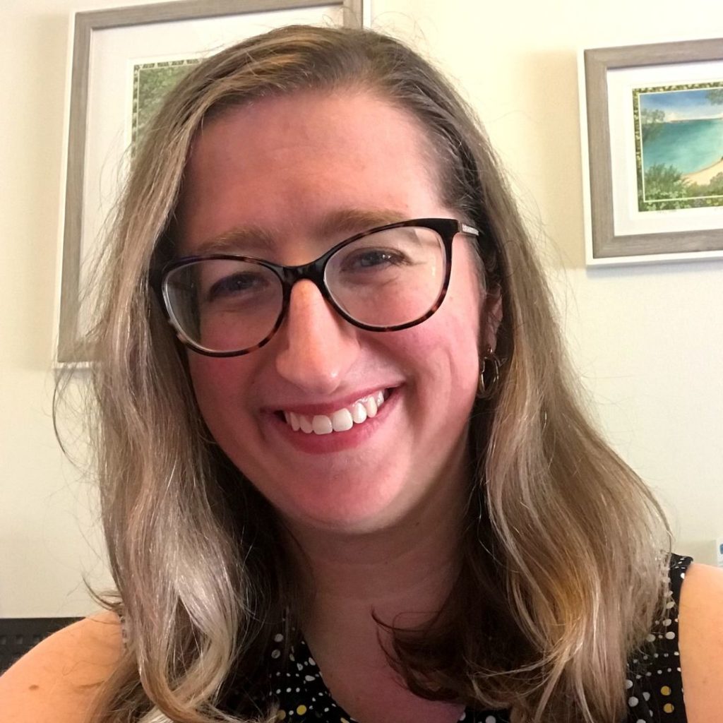 Portrait of a smiling woman with short blonde hair and eyeglasses.